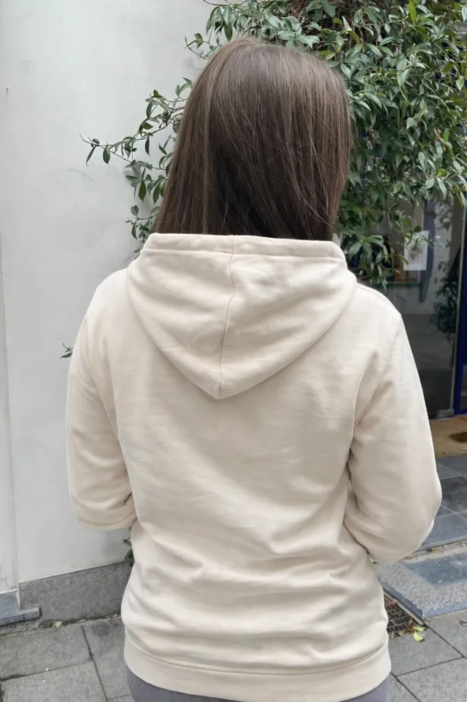 Vrouw in beige hoodie in de tuin.webp